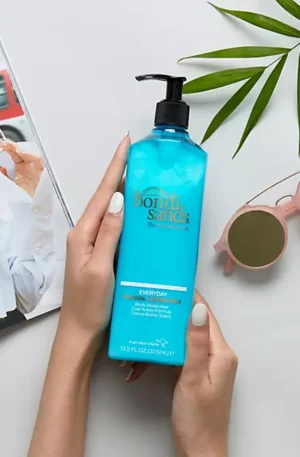 Bondi Sands Tanning Milk bottle against a serene beach backdrop, highlighting its hydrating formula and coconut scent for a natural, streak-free tan